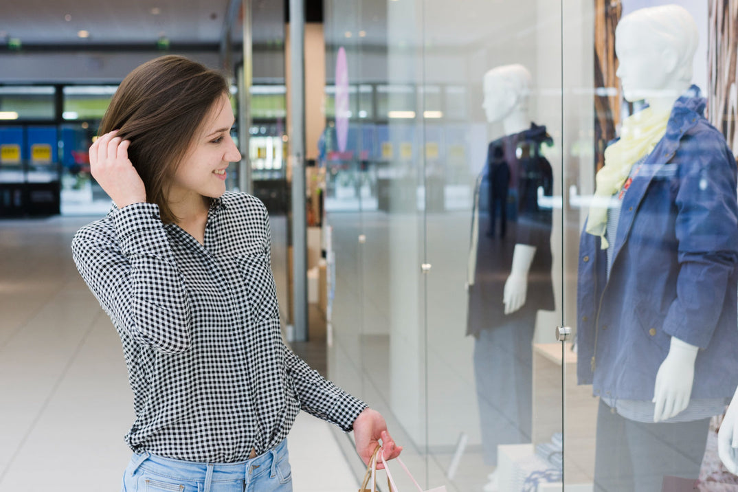 Mujer enfrente del escaparate de una tienda, evaluando su próxima compra.