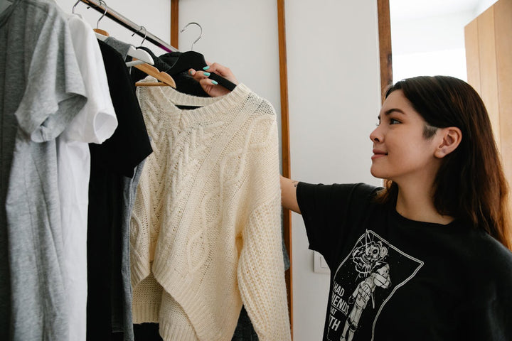 Mujer utilizando un organizador o rack para ropa para optimizar el espacio y mantener el orden en su casa con artículos funcionales y decorativos